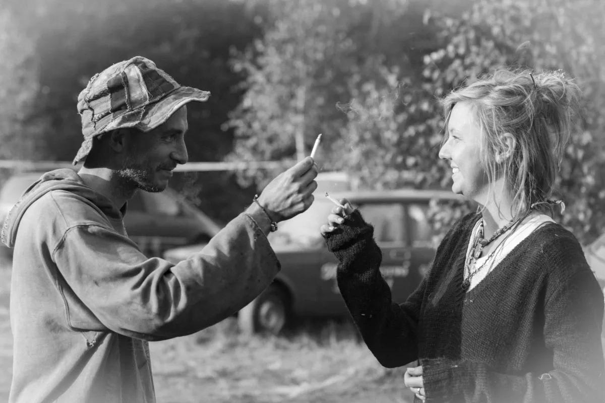 Two older people lighting cigarettes face to face